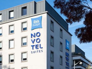 A modern building with 'ibis budget' signage, multiple windows, and balconies. - Novotel Suites Nancy Centre (Nancy)