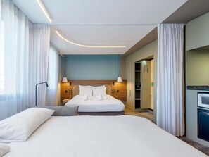 Une chambre d’hôtel avec un grand lit, des lampes de chevet, une armoire et un bureau avec un ordinateur.