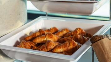A buffet with trays of croissants and a coffee machine.