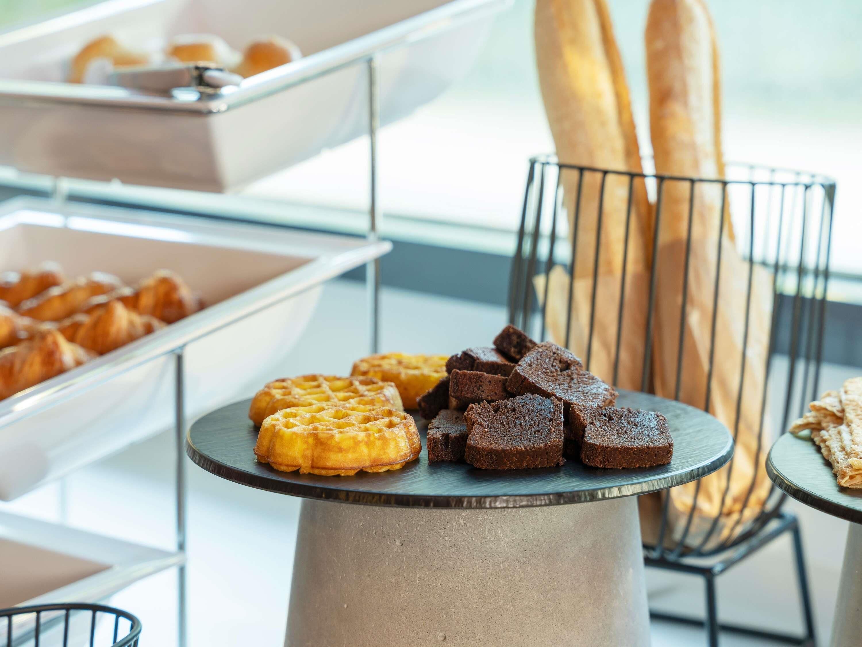 Un bufé con gofres, brownies y pan sobre una mesa.