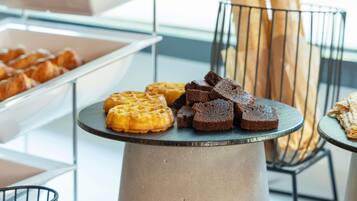 Un bufé con gofres, brownies y pan sobre una mesa.