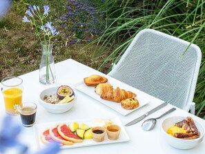 Une table de petit-déjeuner avec des croissants, des fruits et du café.