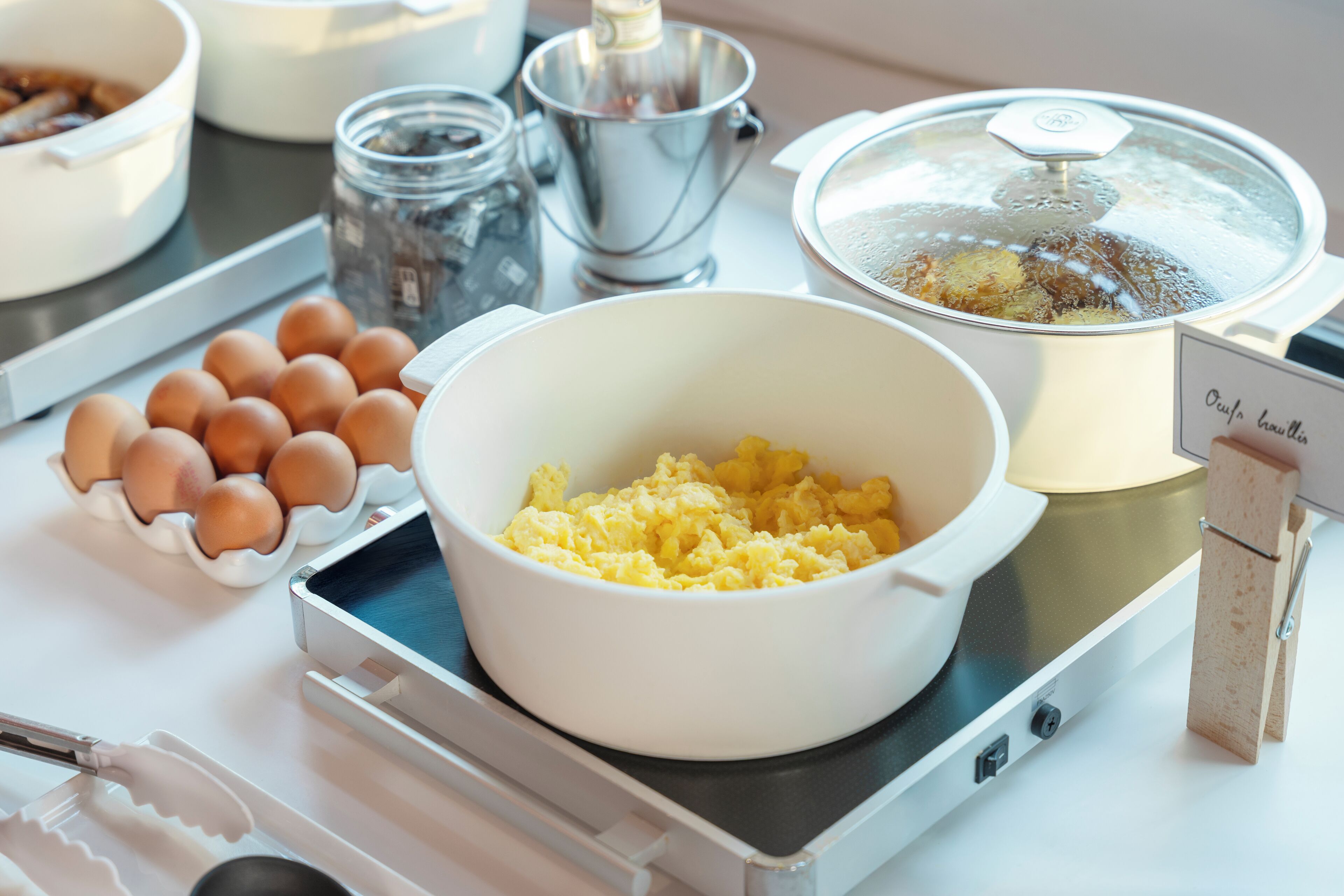 Una encimera de cocina con un bol de huevos revueltos, una olla hirviendo y una bandeja de huevos.