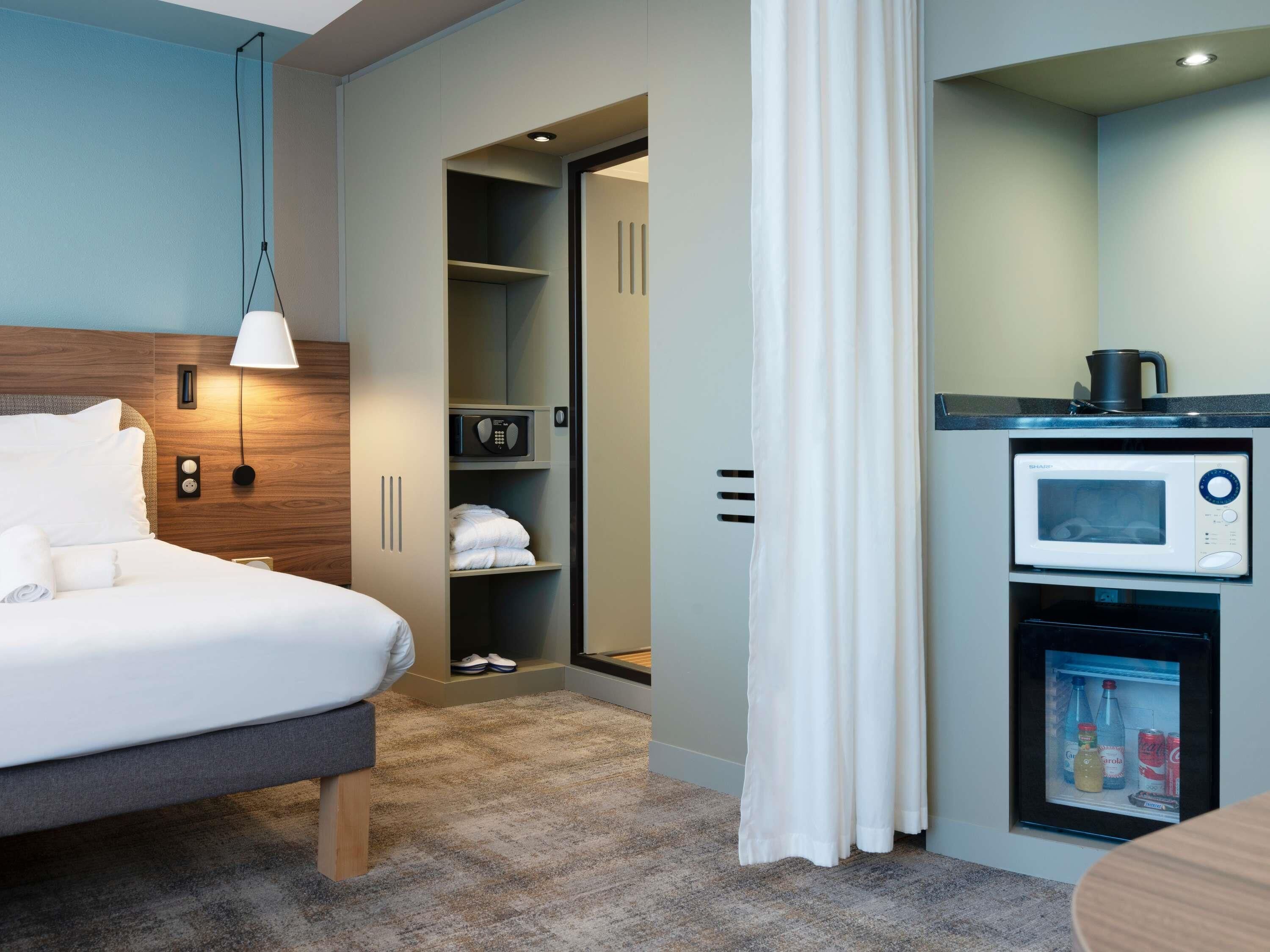Een hotelkamer met een bed, een kledingkast, een magnetron en een minibar.
