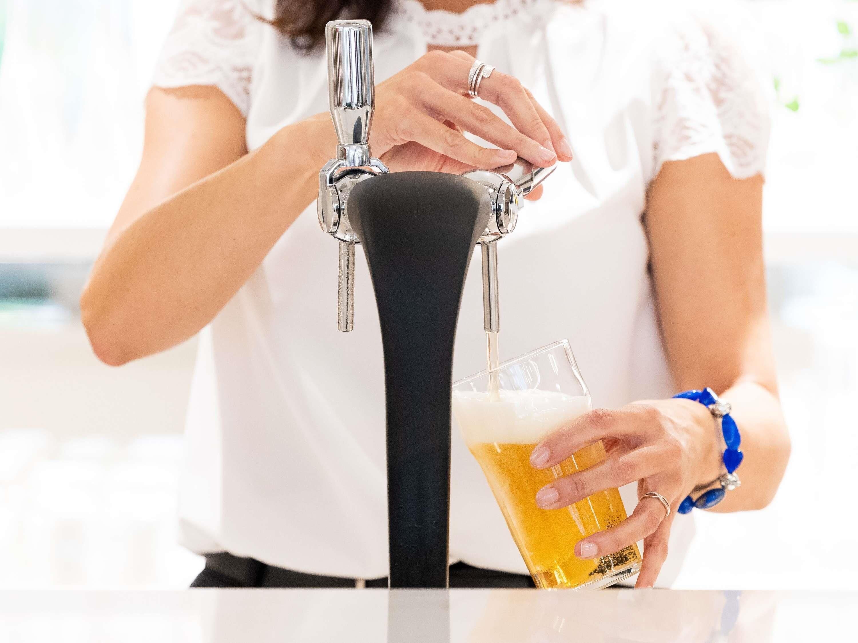 A person pouring beer from a tap into a glass.