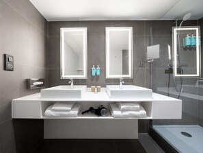 A modern bathroom with two sinks, a large mirror, and a shower enclosure. - Novotel Suites Montpellier (Montpellier)