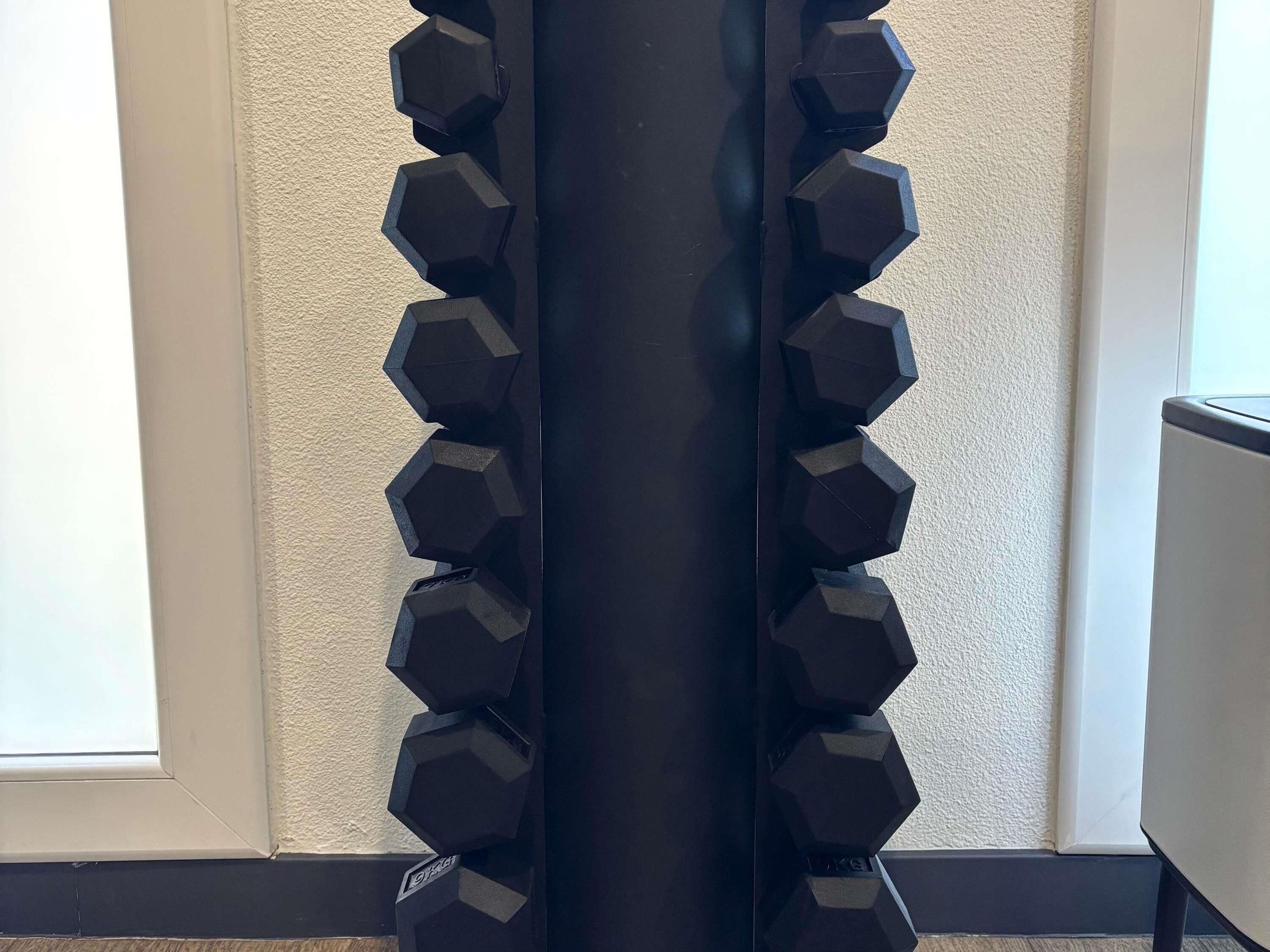 A black cylindrical object surrounded by hexagonal weights.