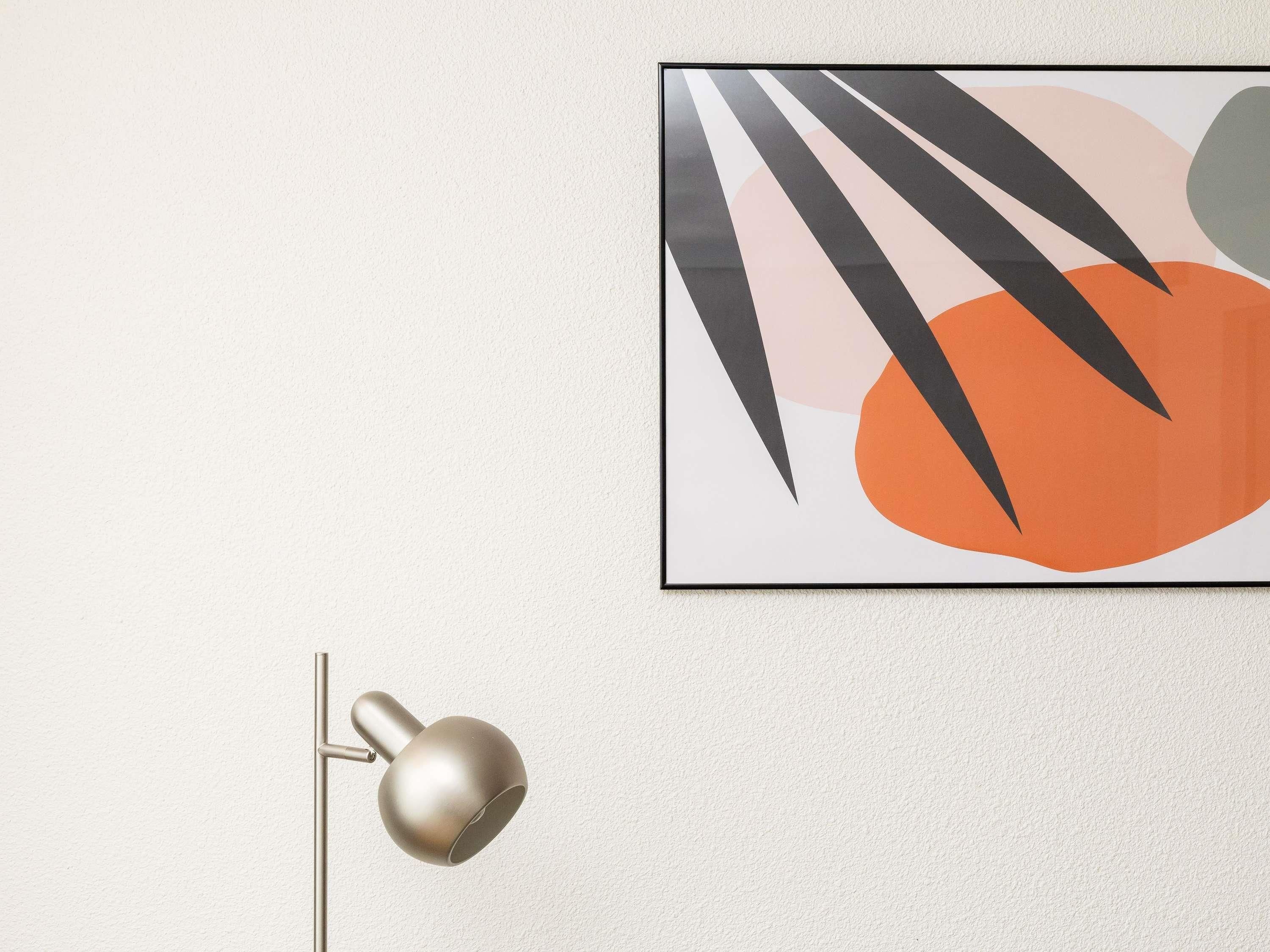 Un quadro astratto incorniciato con forme geometriche e una moderna lampada da terra.