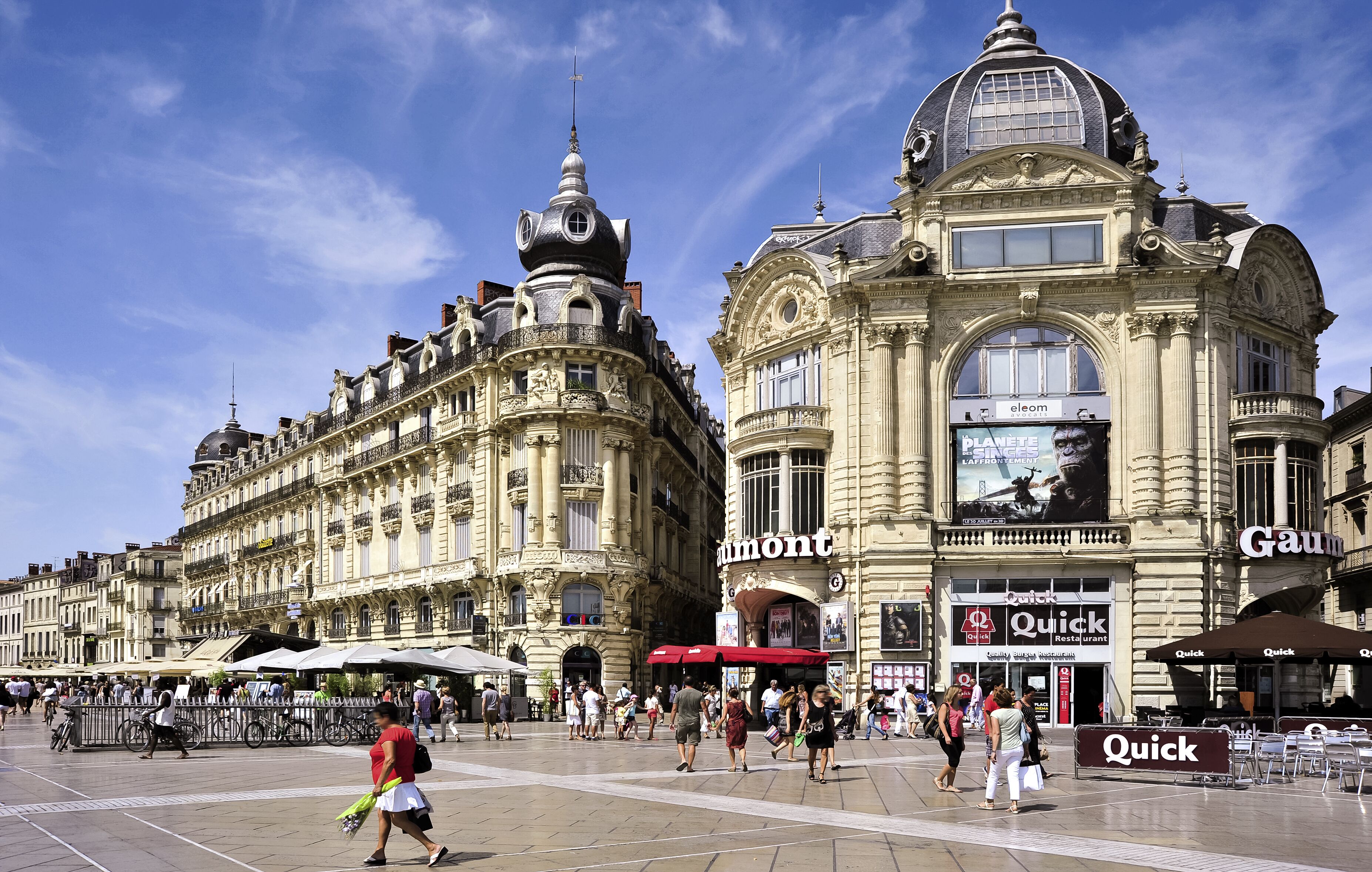 Un edificio histórico con arquitectura ornamentada, una cúpula destacada y un gran anuncio del restaurante 'Quick'.