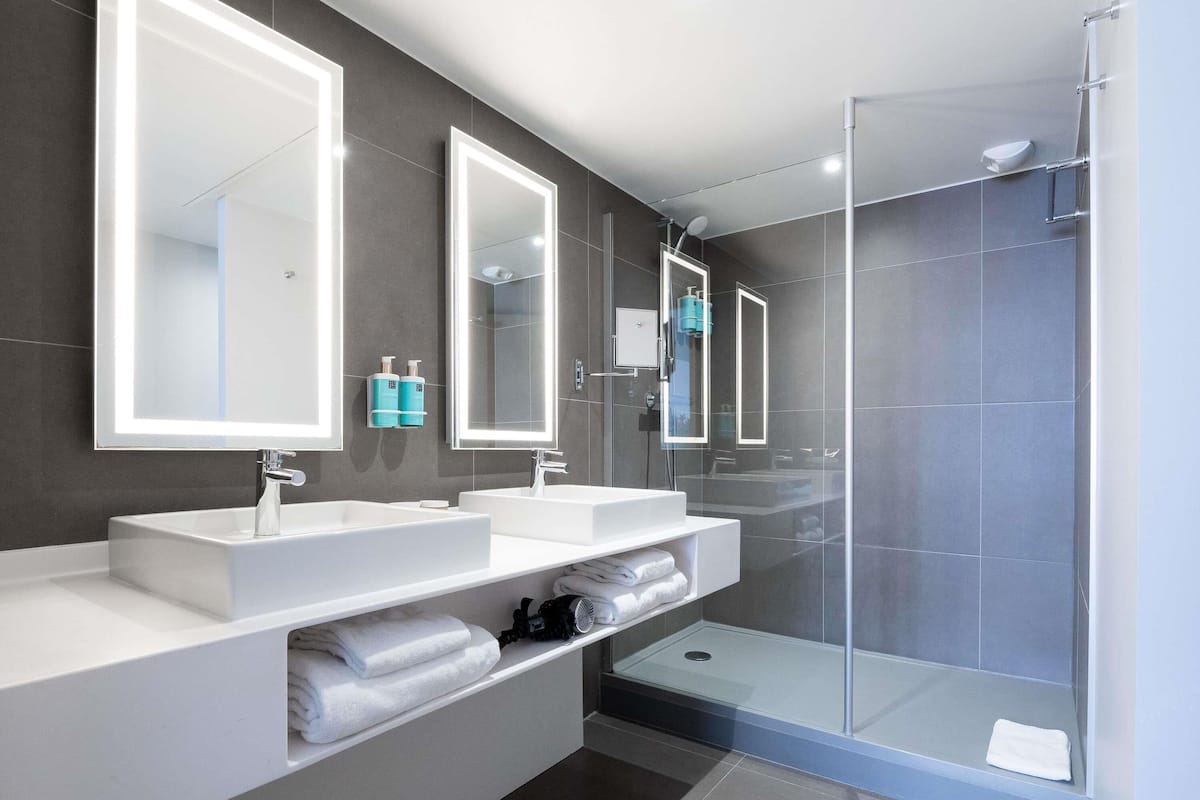 A modern bathroom with two sinks, a glass shower enclosure, and built-in mirrors.