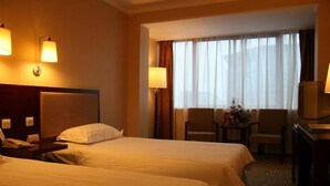 Een hotelkamer met twee bedden, een bureau, een stoel en een tafeltje met een lamp.