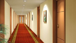 Een hotelgang met een rode loper, houten deuren en inbouwverlichting.