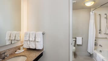 A modern bathroom with a granite countertop, a sink, a toilet, a shower with a glass door, and a bathtub.