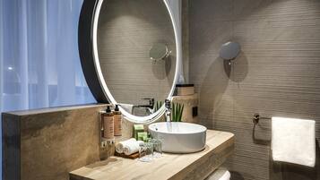 A modern bathroom with a round mirror, a white sink, and a towel rack.