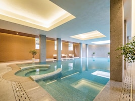 Una piscina techada, sillones reclinables de piscina