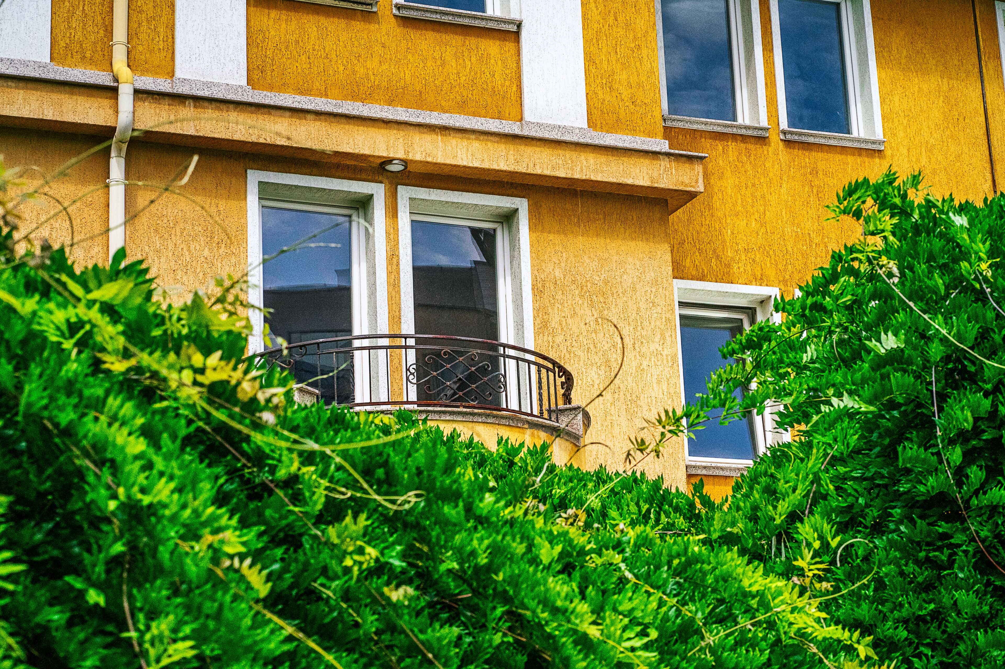 Ein gelbes Gebäude mit vielen Fenstern und einem Balkon.