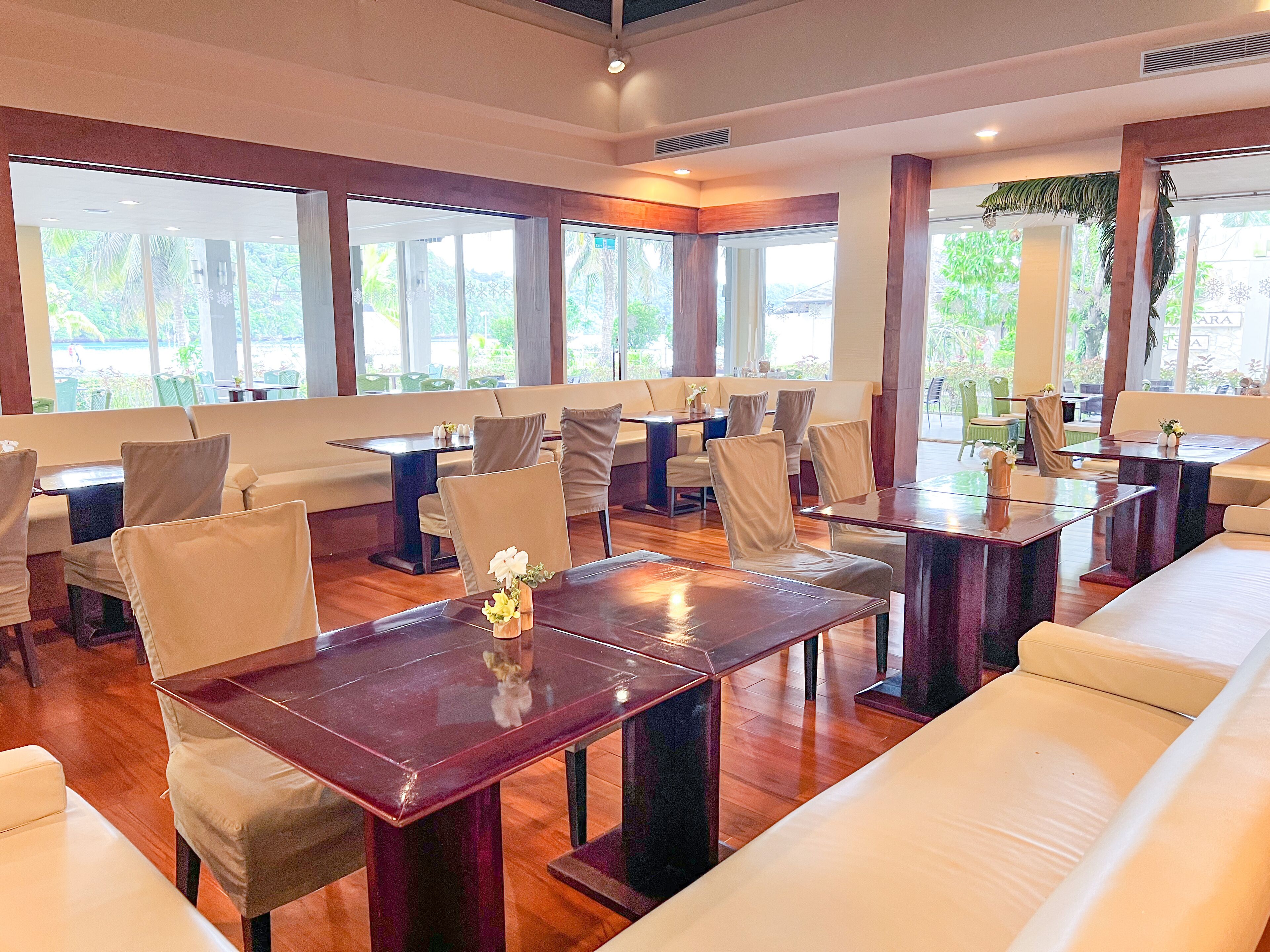 A spacious restaurant with high ceilings, large windows, and a variety of seating arrangements including tables and booths.