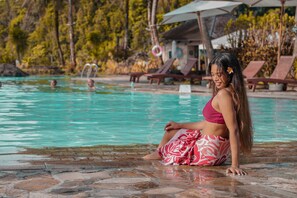 Una piscina al aire libre, sombrillas, tumbonas