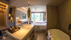 Un baño de hotel moderno con una bañera grande, un tocador con espejo y una zona de ducha.