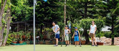 Un grupo de personas jugando croquet en un campo cubierto de césped, con una bandera marcada con el número 6.