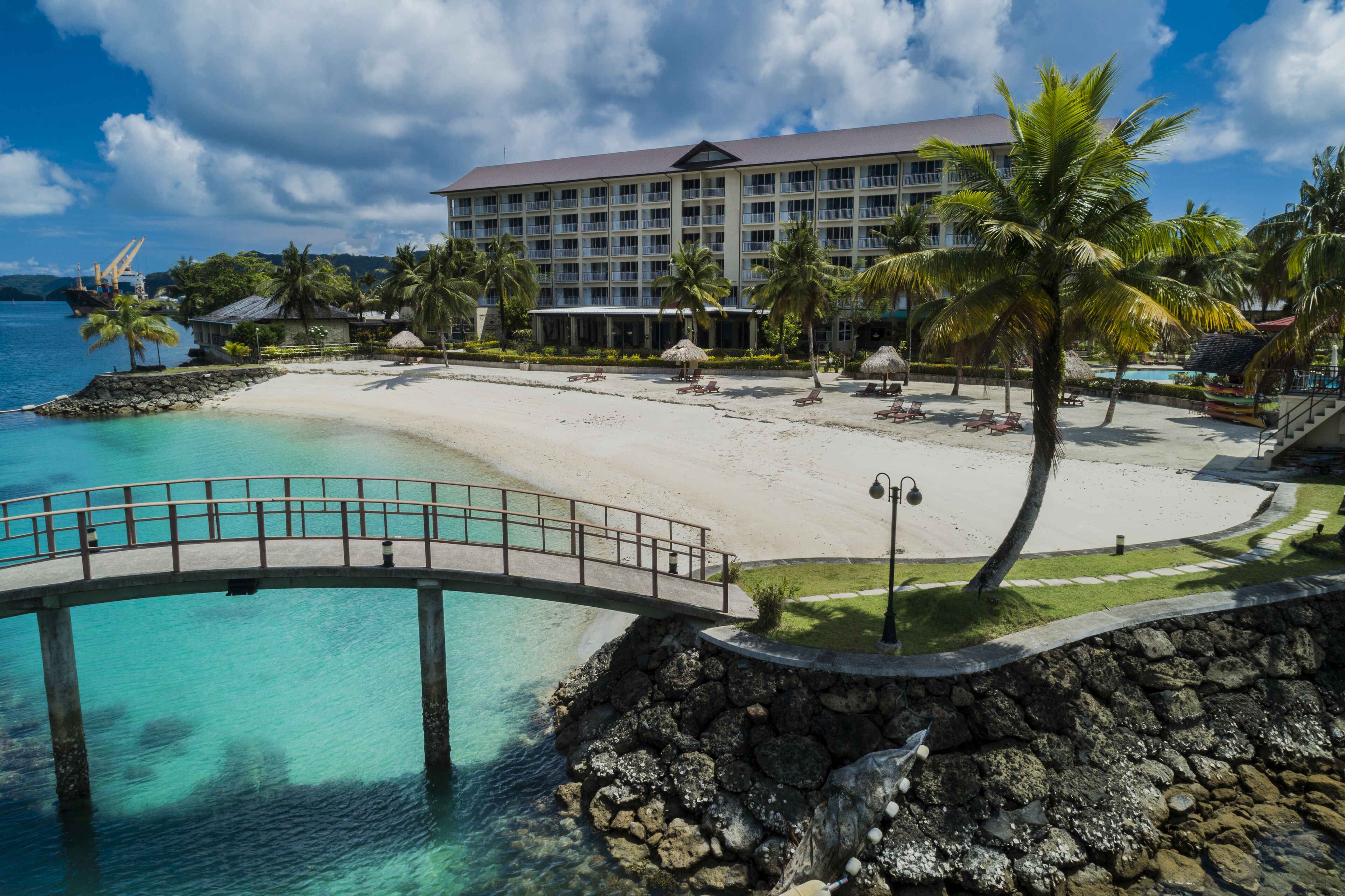 A resort with a beach, a bridge, and a pool.