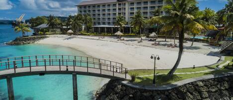 A resort with a beach, a bridge, and a pool.