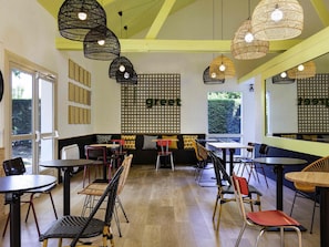 Ein Restaurantinneres mit mehreren Tischen und Stühlen, einer hohen Decke mit freiliegenden Balken und einer an der Wand befestigten Speisekarte.