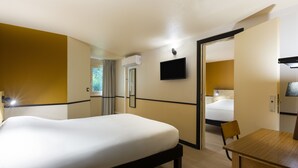 Une chambre d’hôtel avec un grand lit, un bureau et un téléviseur fixé au mur.