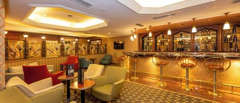 Una zona de bar con varios taburetes, una barra y una sala de estar con sillas.