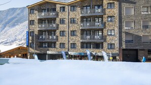 A multi-story hotel with balconies, a restaurant, and a ski resort in the background. - Apartaments Shusski by Nexta. (Encamp)