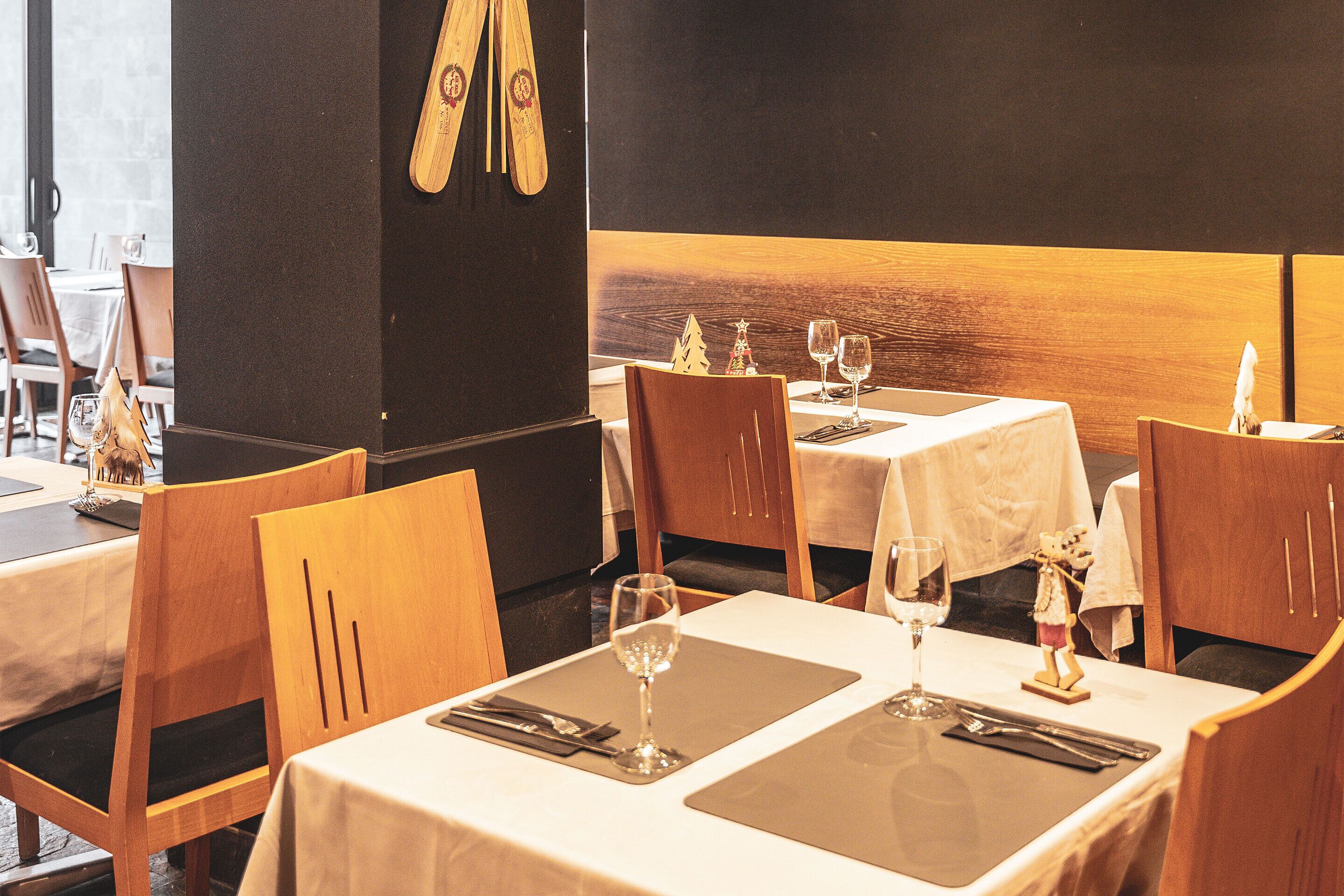A restaurant with wooden chairs and tables, each set with a wine glass, cutlery, and a napkin.