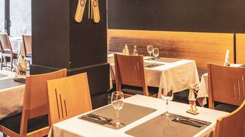 A restaurant with wooden chairs and tables, each set with a wine glass, cutlery, and a napkin.