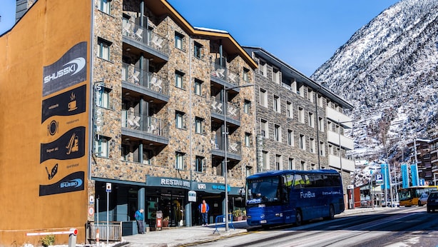 A multi-story hotel with a stone facade, balconies, and a ski sign. - Apartaments Shusski by Nexta. (Encamp)