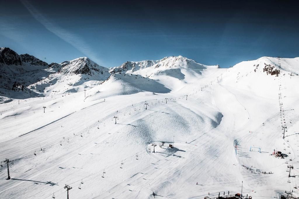Pista de esquí nevada con remontes y cielo despejado.