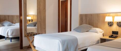 Una habitación de hotel con cama, mesitas de noche, un espejo y una lámpara de pared.