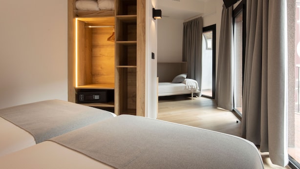 A bedroom with a wooden wardrobe, a bed, and a view through an open door.