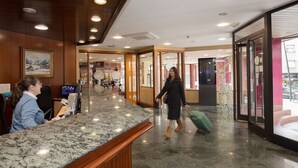A hotel lobby with a reception desk, a large window, and a decorative tree.