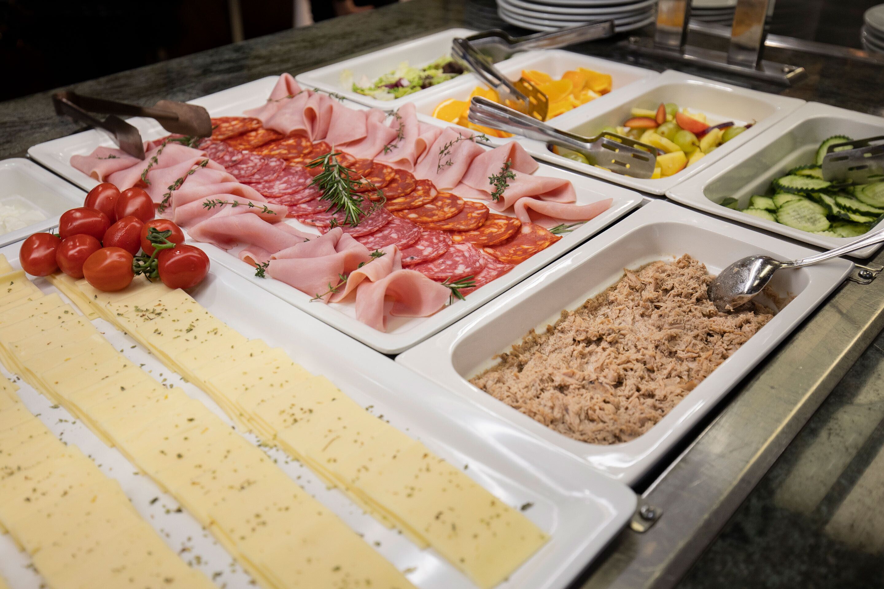 A buffet with various food items including meats, cheeses, and fruits.