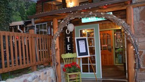 A rustic wooden building with a stone facade, a wooden fence, and a sign that reads "OTEL". - Sitzmark Chalet Inn (Ruidoso)