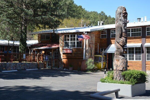 A wooden building with a flag, a statue, and a stone wall.