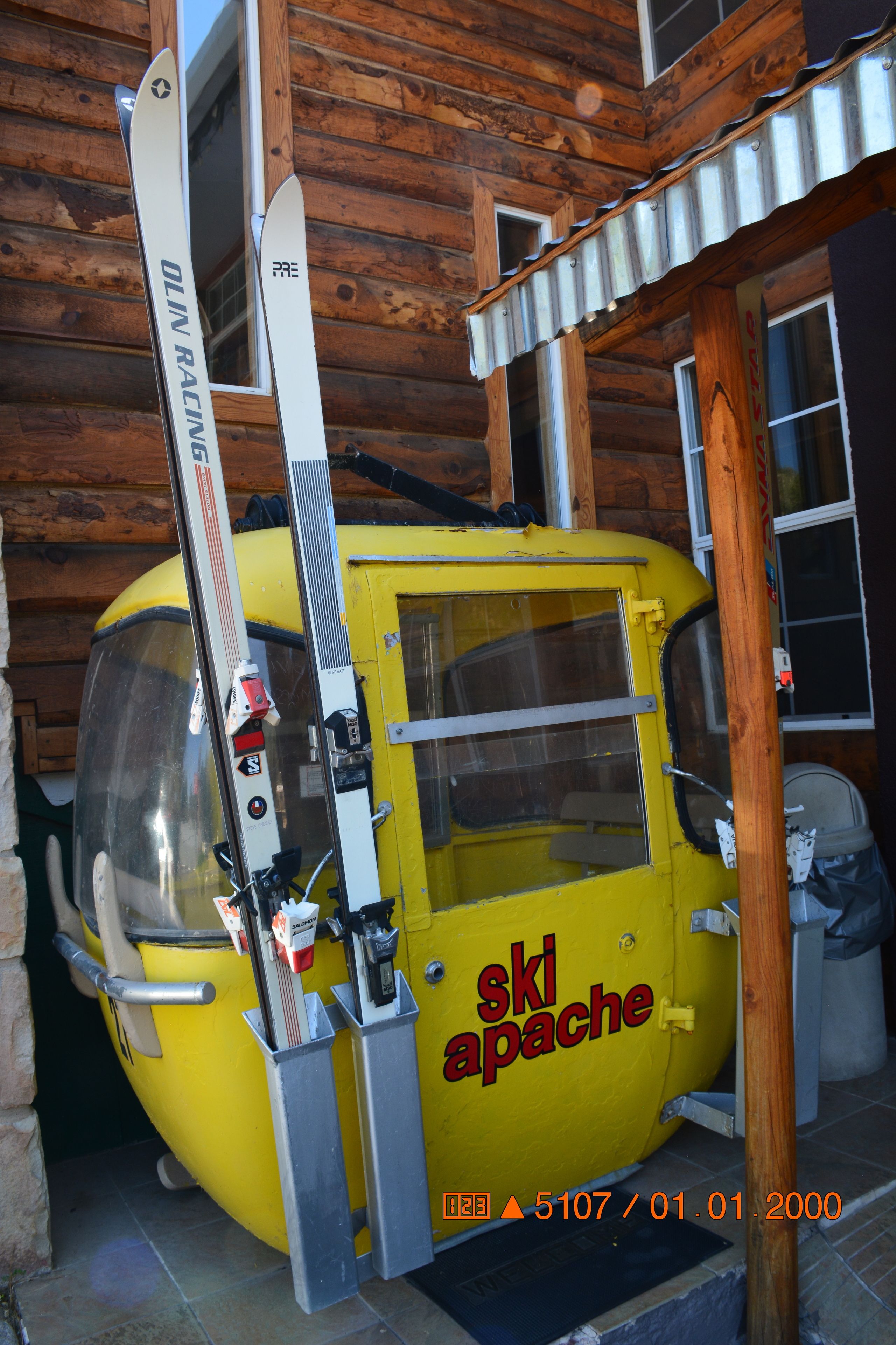 Un telesilla amarillo con el texto "ski apache" en él, adosado a una edificación de madera.