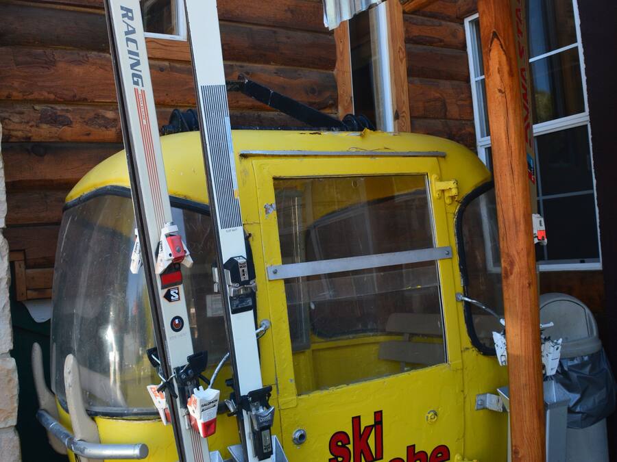 A yellow ski lift with the text "ski apache" on it, attached to a wooden building.