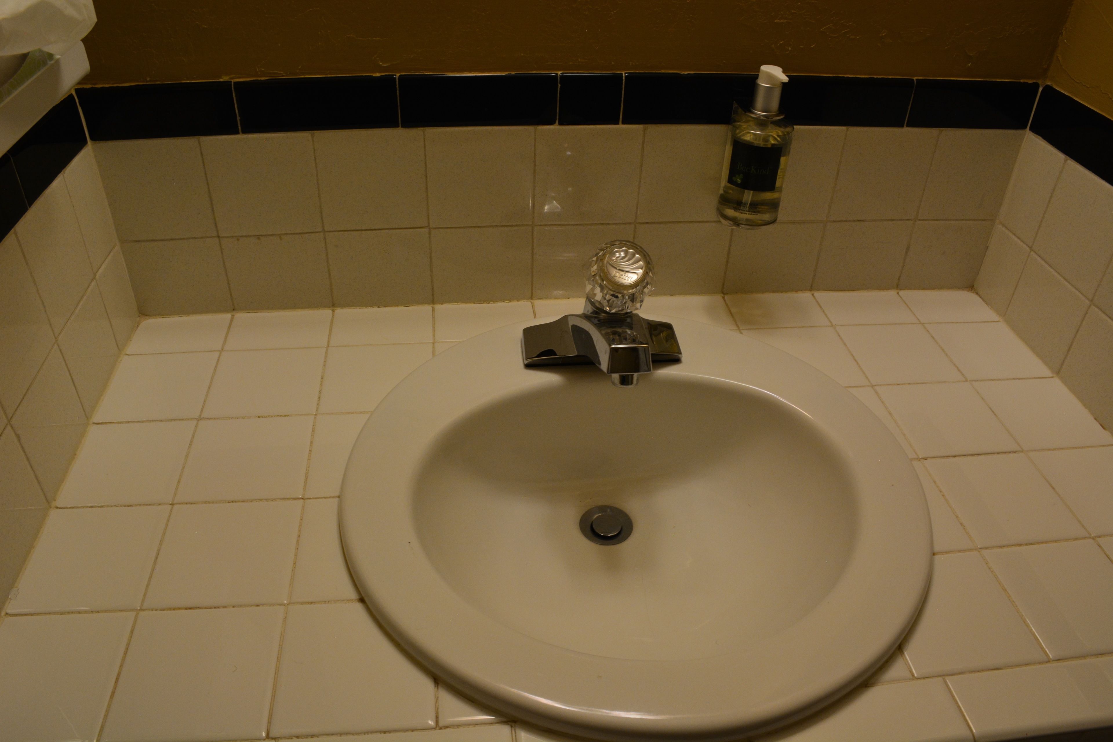 A bathroom sink with a mirror, a faucet, and a soap dispenser.
