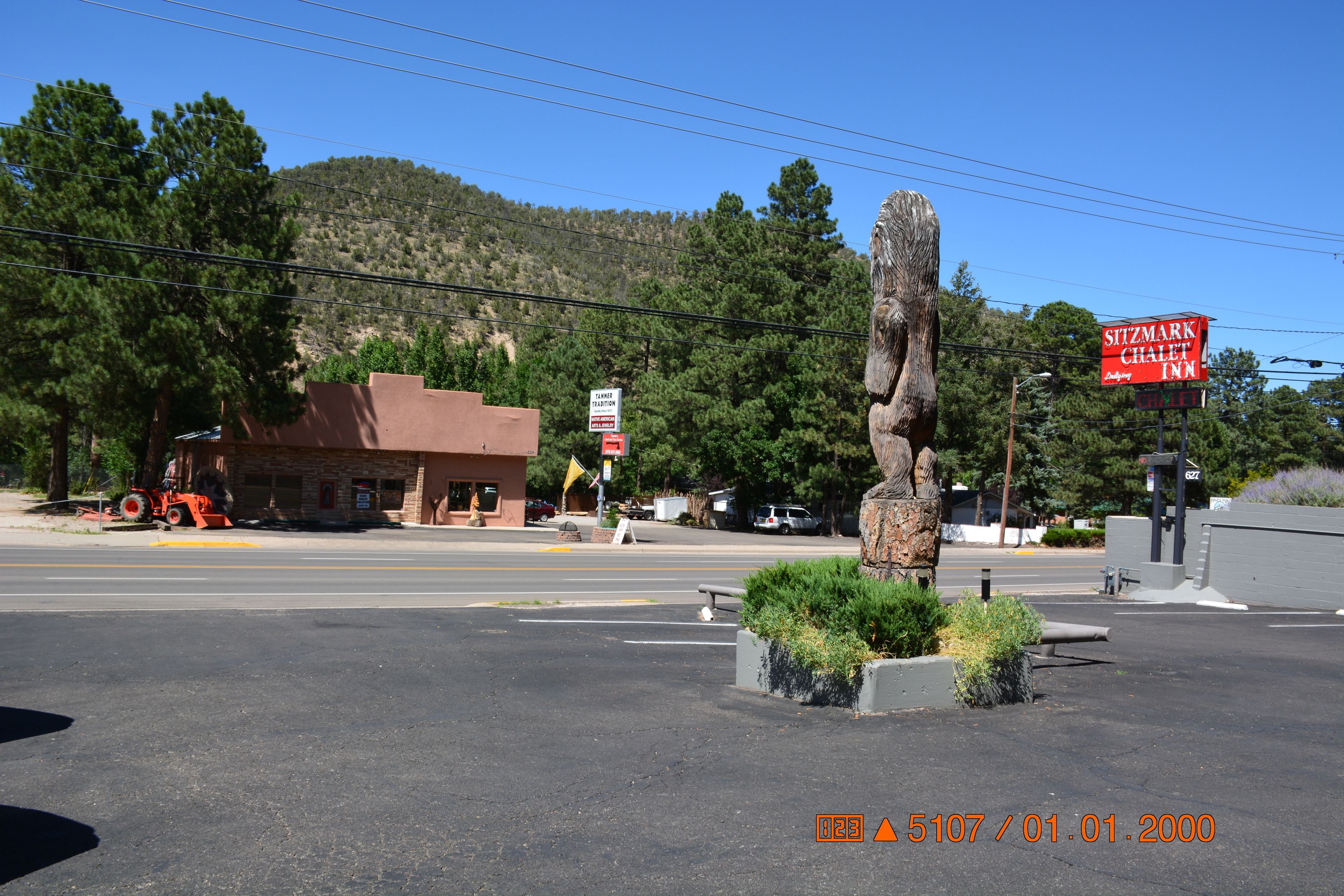 A parking lot with a stone sculpture, a building with a 'Sitzmark Chalet Inn' sign, and a mountain in the background.