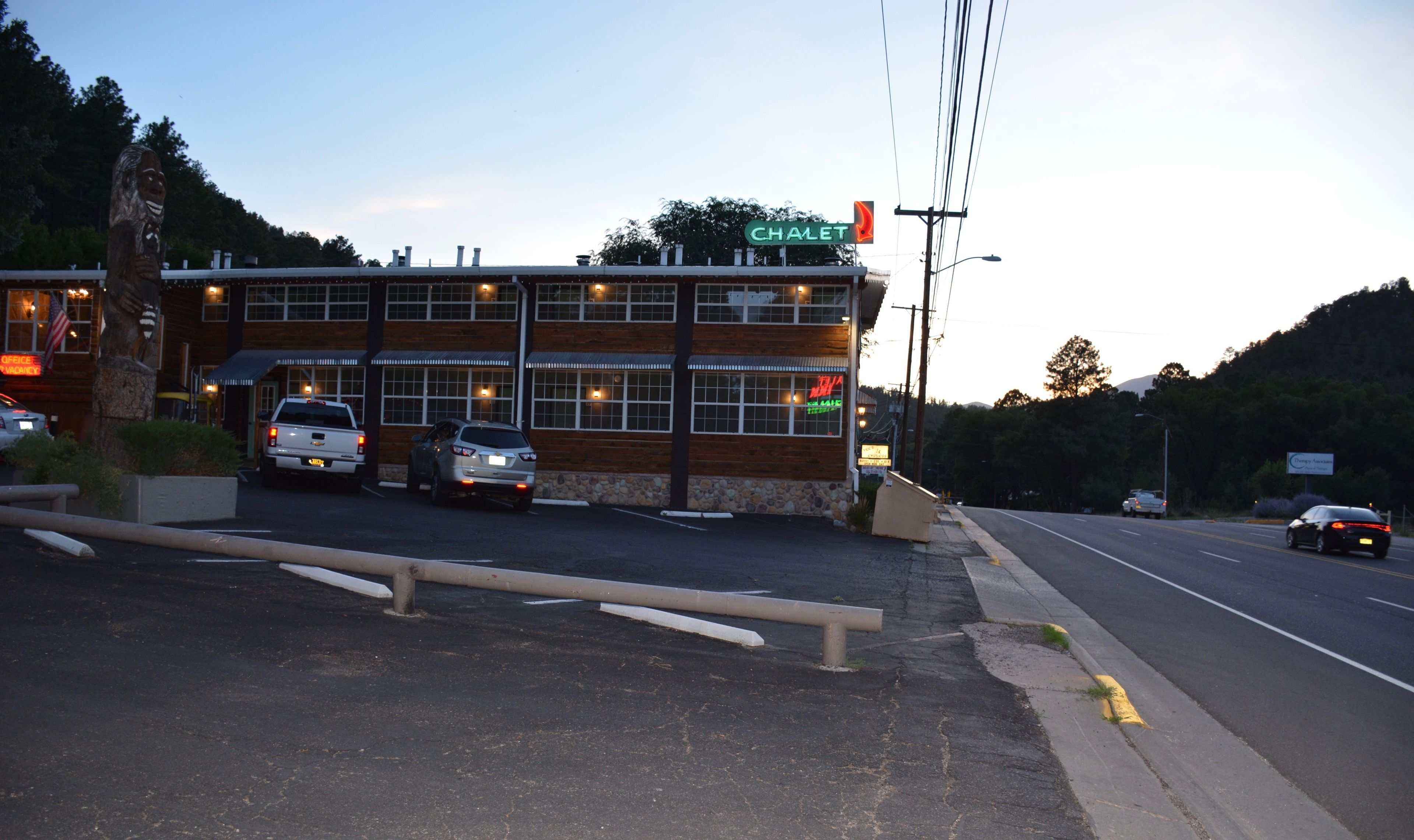 A building with a sign reading "CHALET" and a parking lot with several vehicles.