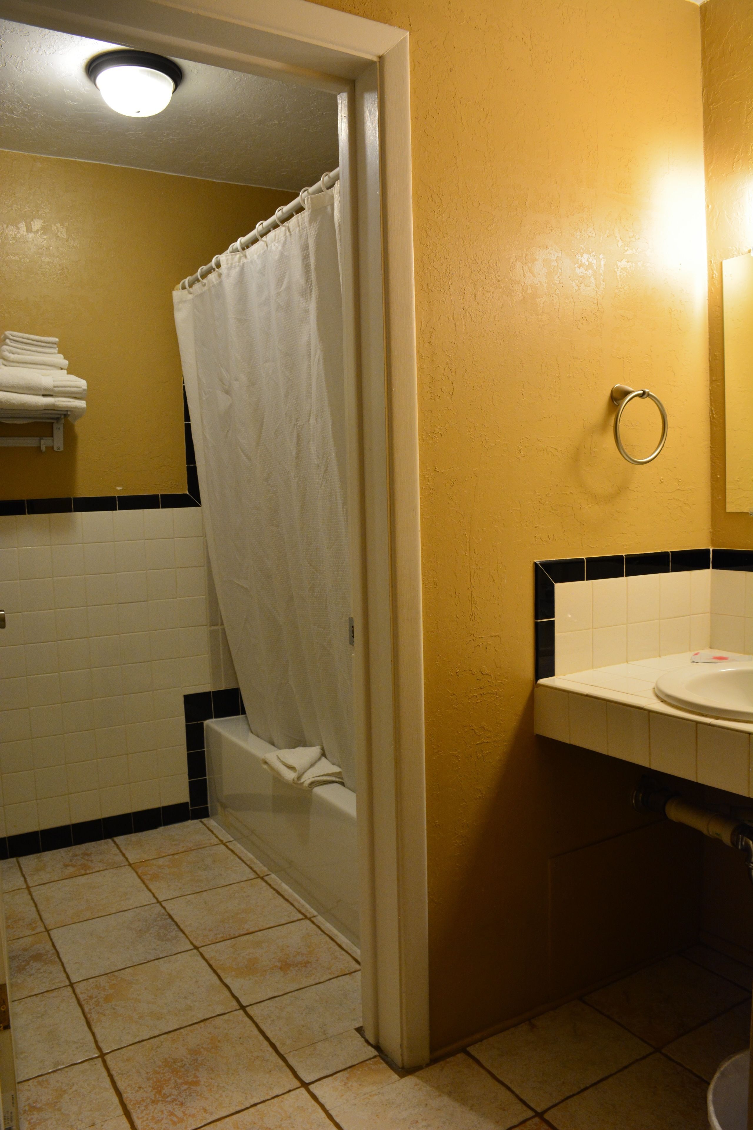 A bathroom with a white bathtub, a white sink, and a yellow wall.