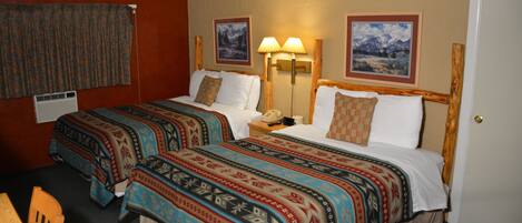 A hotel room with two beds, a nightstand, a lamp, and a door.