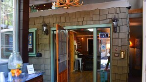 A restaurant interior with a stone facade, a sign reading "OPEN", and a security camera. - Sitzmark Chalet Inn (Ruidoso)