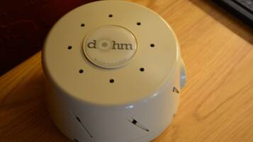 A white device with the text "dohm" on its top, placed on a wooden surface.