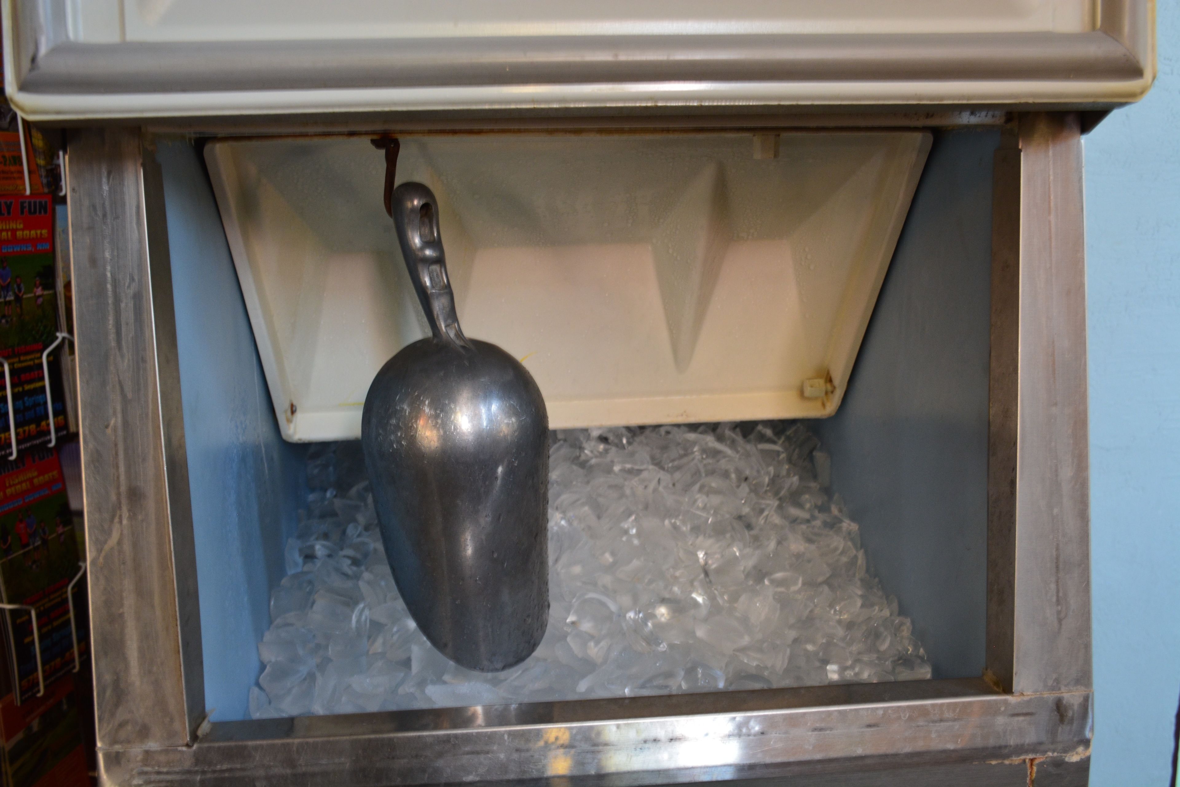 A metal scoop over a container filled with ice.